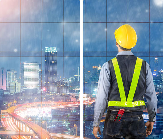 ouvrier de chantier devant des vitres contemplant la ville de nuit