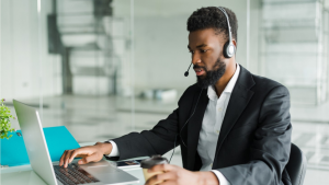 homme avec un casque devant son bureau et son ordinateur en conversation