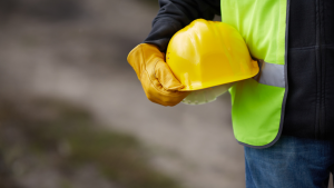 homme tenant un casque de chantier et portant un gilet