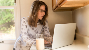 femme travaillant sur son ordinateur avec un verre de lait