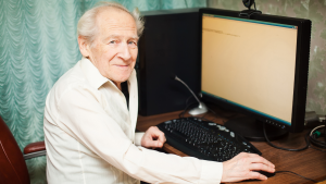 personne âgée en chemise blanche devant son ordinateur