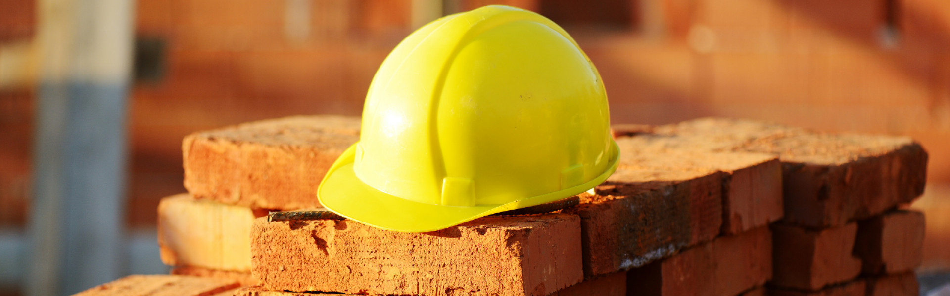 casque de chantier jaune sur des briques orange