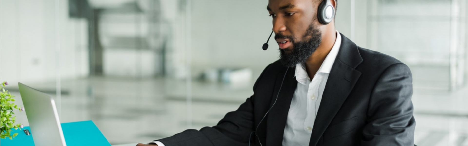 homme avec un casque devant son bureau et son ordinateur en conversation