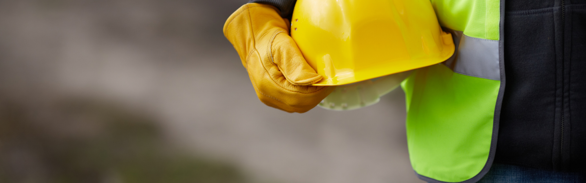 homme tenant un casque de chantier et portant un gilet
